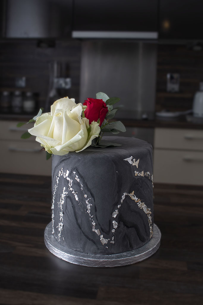 Elegant black and silver decorated cake with white and red roses
