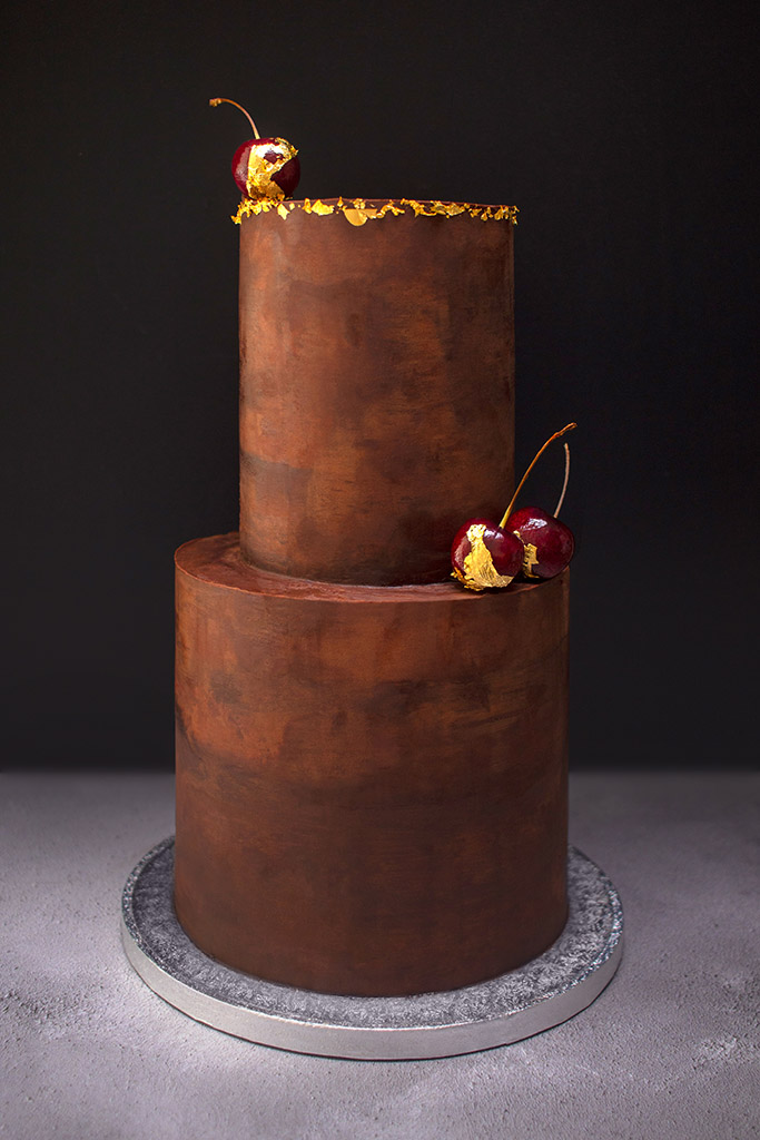 Indulgent two-tier chocolate cake with cherries and gold trim