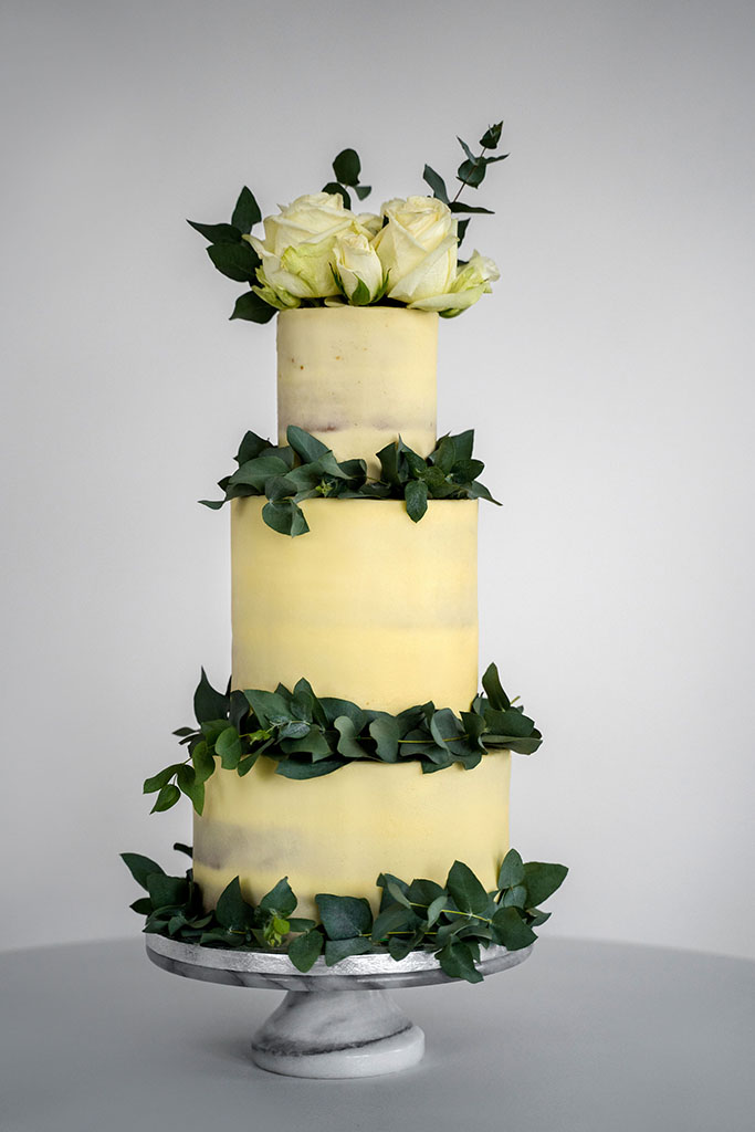 A white wedding cake decorated with leaves and flowers